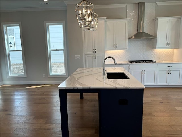 kitchen featuring stainless steel gas stovetop, sink, white cabinets, light stone countertops, and wall chimney exhaust hood