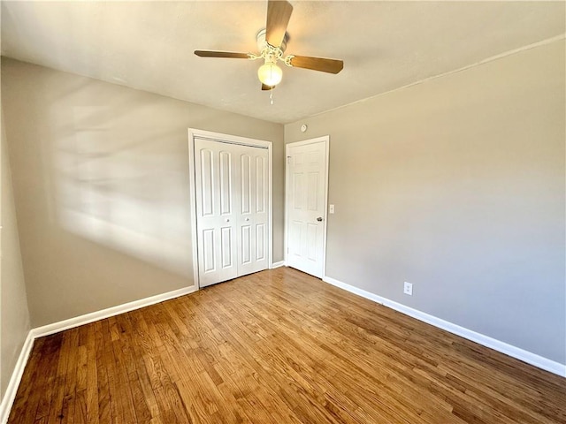 unfurnished bedroom featuring ceiling fan, a closet, wood finished floors, and baseboards