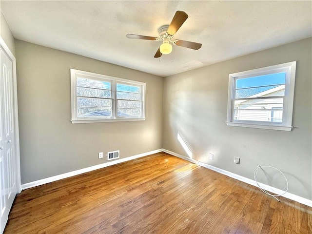 unfurnished bedroom featuring baseboards, visible vents, ceiling fan, wood finished floors, and a closet