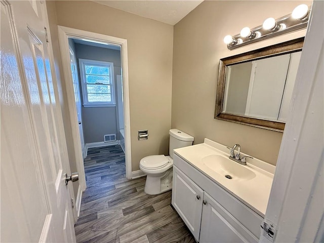 full bath with a tub to relax in, toilet, vanity, visible vents, and baseboards