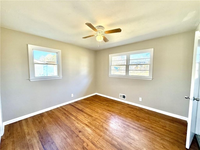 unfurnished room with ceiling fan, wood finished floors, visible vents, and baseboards