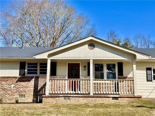 view of front of home featuring crawl space, covered porch, roof with shingles, and brick siding