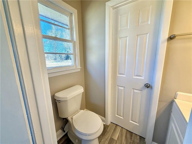 bathroom with wood finished floors, toilet, and baseboards