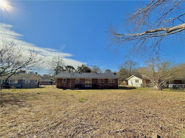 view of front of house featuring brick siding, a front yard, and fence