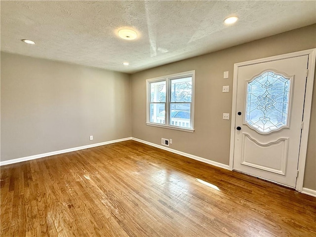 entryway featuring visible vents, a textured ceiling, baseboards, and wood finished floors