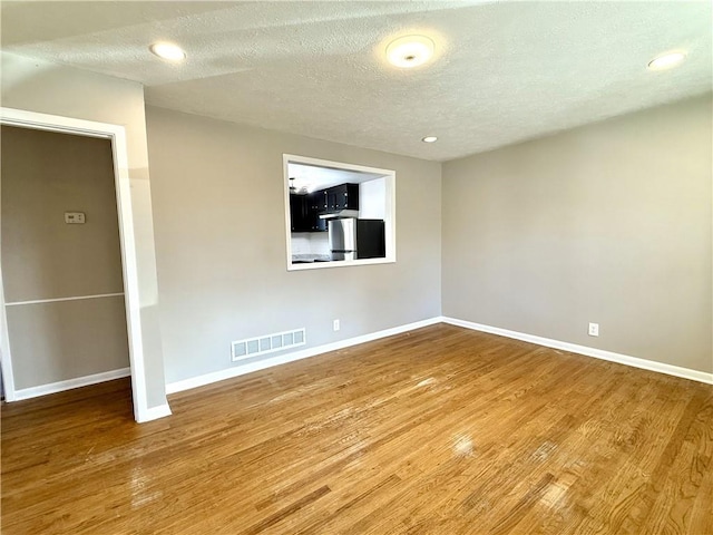 spare room with baseboards, visible vents, and wood finished floors