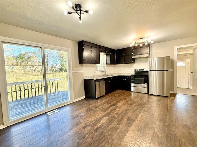 kitchen featuring stainless steel appliances, dark wood finished floors, a notable chandelier, and a sink