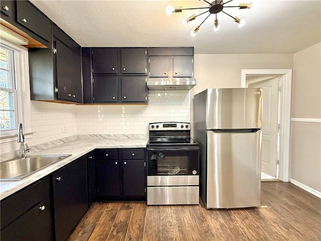 kitchen with dark wood finished floors, light countertops, appliances with stainless steel finishes, a sink, and under cabinet range hood