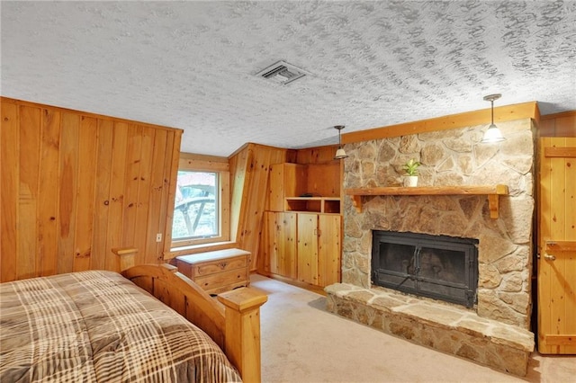 carpeted bedroom featuring a stone fireplace, a textured ceiling, and wooden walls