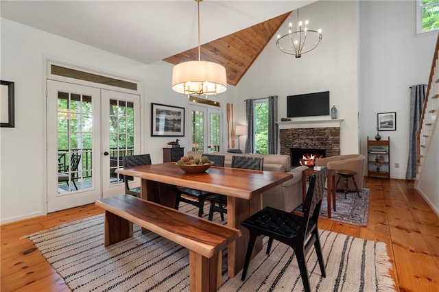 367 Windflower Dr, Big Canoe, GA 30143 - dining area featuring french doors, high vaulted ceiling, a chandelier, light wood finished floors, and a stone fireplace