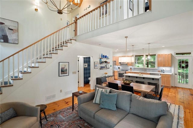 367 Windflower Dr, Big Canoe, GA 30143 - living room featuring a towering ceiling, light wood-type flooring, a chandelier, stairs, and recessed lighting