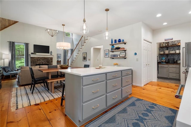 367 Windflower Dr, Big Canoe, GA 30143 - kitchen featuring gray cabinets, light wood finished floors, a center island, a stone fireplace, and open floor plan
