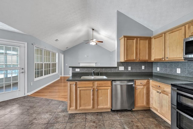 kitchen featuring a sink, dark countertops, stainless steel appliances, and lofted ceiling