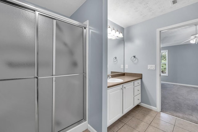 full bath featuring tile patterned flooring, vanity, baseboards, a ceiling fan, and a stall shower