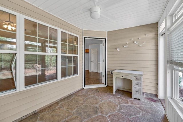 unfurnished sunroom featuring a ceiling fan
