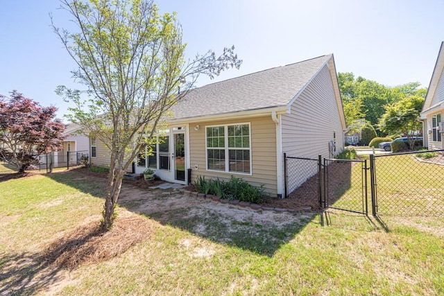 view of front facade featuring fence, a gate, a shingled roof, and a front lawn
