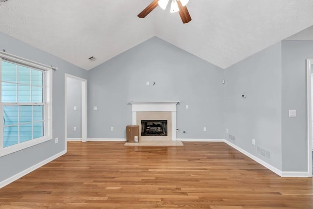 unfurnished living room with ceiling fan, vaulted ceiling, light wood-type flooring, and visible vents