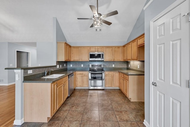 kitchen with stainless steel appliances, ceiling fan, dark countertops, and a sink