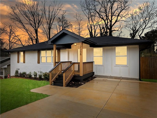 ranch-style home featuring board and batten siding, fence, and a lawn