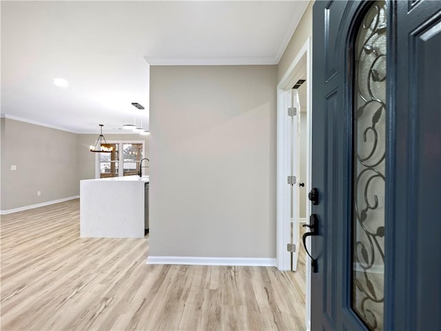 entrance foyer with light wood-style floors, a notable chandelier, baseboards, and crown molding