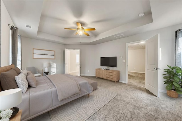 carpeted bedroom featuring a raised ceiling and ceiling fan