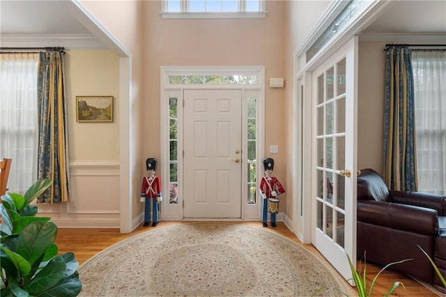 entrance foyer with crown molding, a healthy amount of sunlight, and light hardwood / wood-style floors