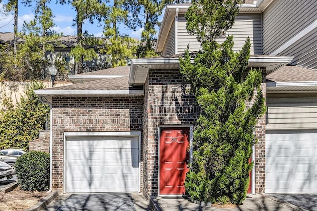 exterior space with brick siding, driveway, a shingled roof, and a garage