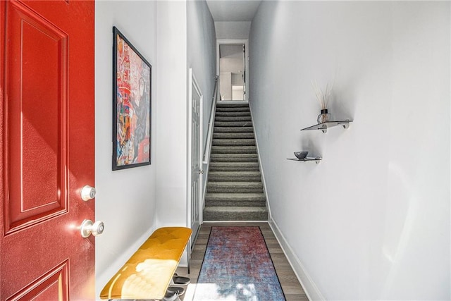 interior space with stairs, dark wood-style floors, and baseboards