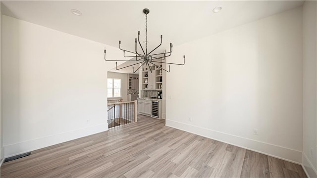 unfurnished dining area featuring recessed lighting, light wood-type flooring, baseboards, and a chandelier