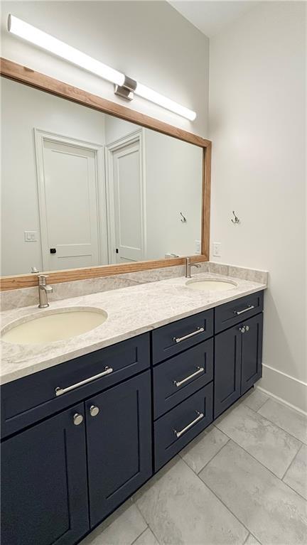 full bath featuring a sink, baseboards, and double vanity