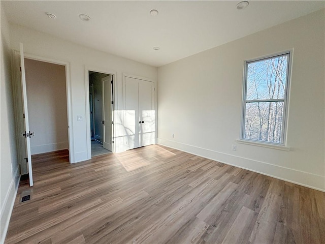 unfurnished bedroom with light wood-style flooring, visible vents, and baseboards