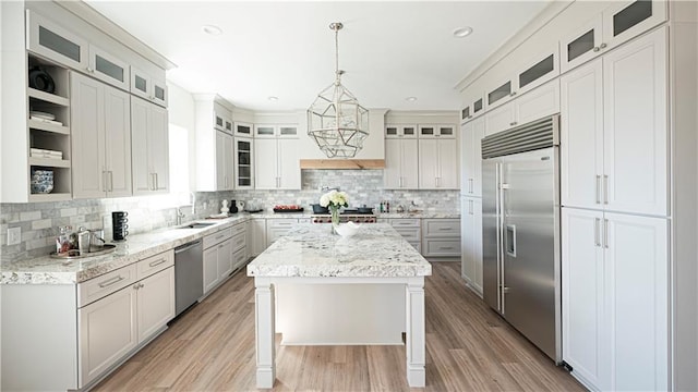 kitchen featuring light stone counters, a kitchen island, light wood-style flooring, a sink, and stainless steel appliances