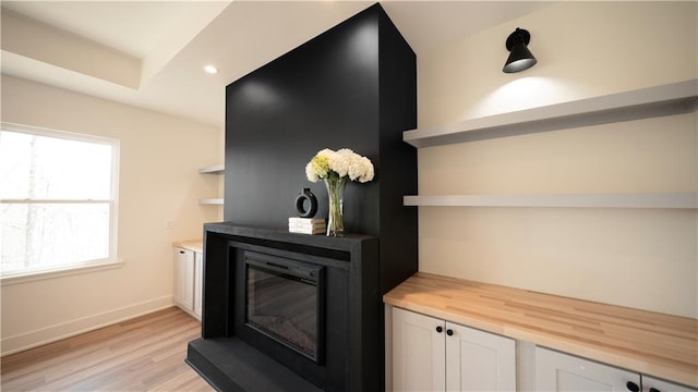 details featuring a glass covered fireplace, recessed lighting, baseboards, and wood finished floors