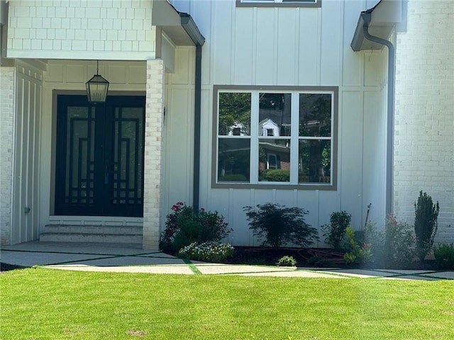 property entrance featuring board and batten siding and a yard