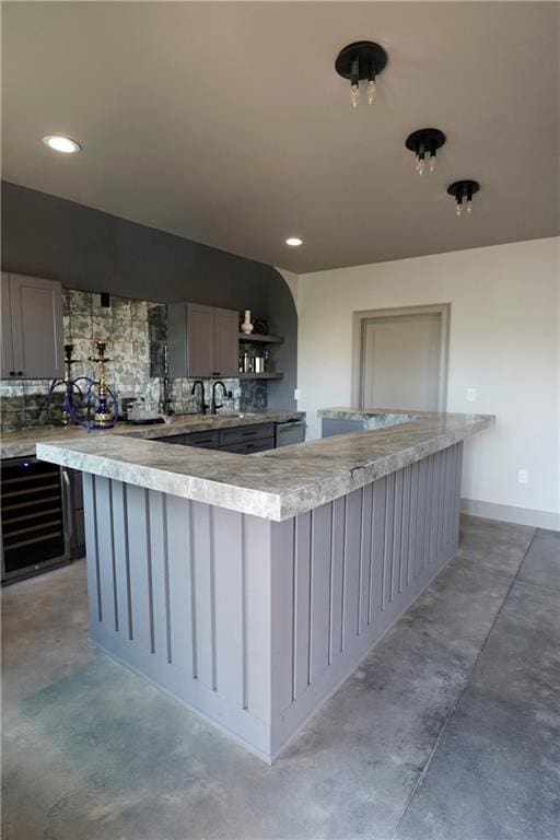 kitchen with light countertops, backsplash, gray cabinets, and concrete flooring