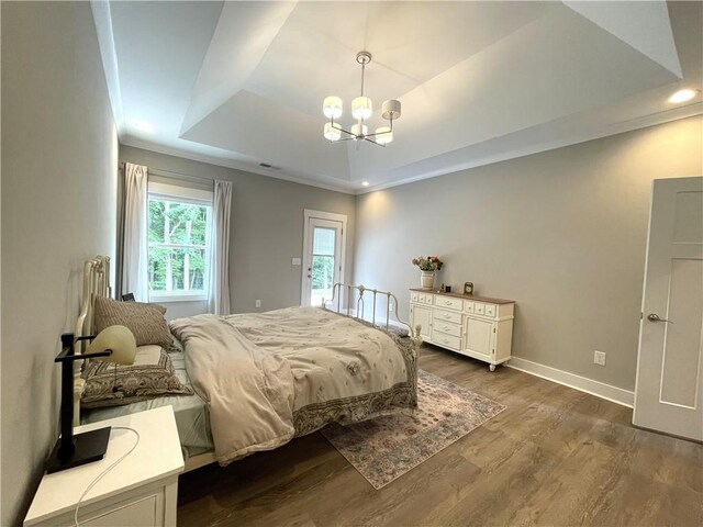 bedroom featuring a tray ceiling, dark hardwood / wood-style floors, and a chandelier