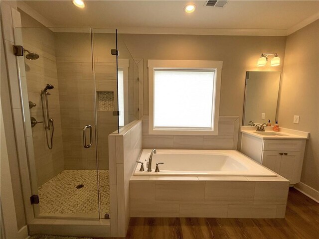 bathroom featuring ornamental molding, vanity, hardwood / wood-style floors, and plus walk in shower