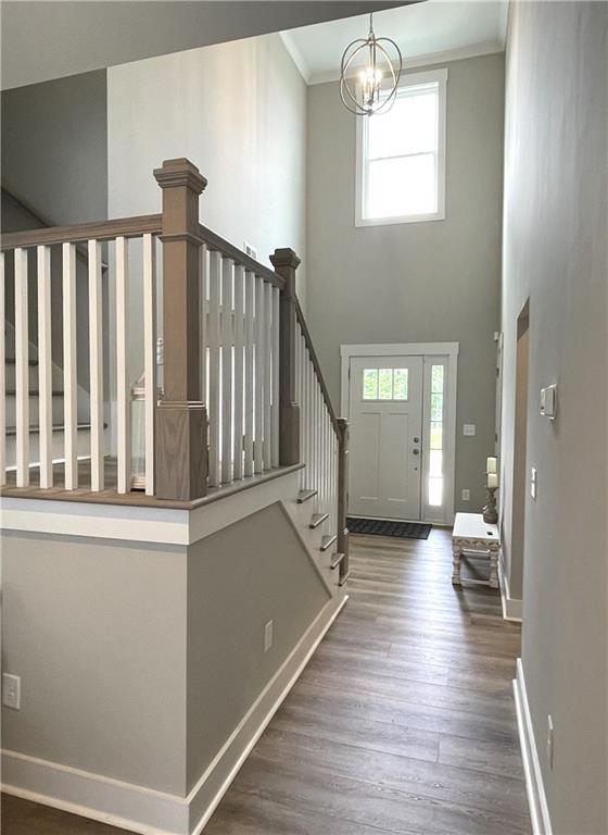 foyer with ornamental molding, dark hardwood / wood-style floors, a chandelier, and plenty of natural light