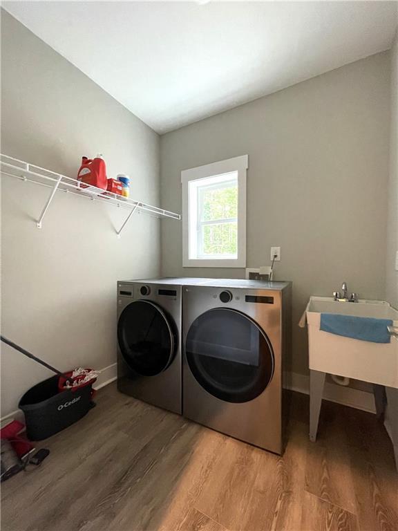 laundry room with hardwood / wood-style flooring, sink, and washer and dryer