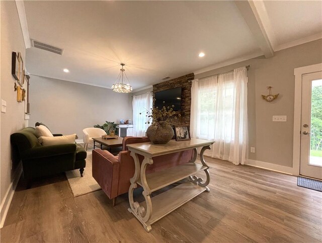 living room with wood-type flooring, crown molding, an inviting chandelier, and beamed ceiling