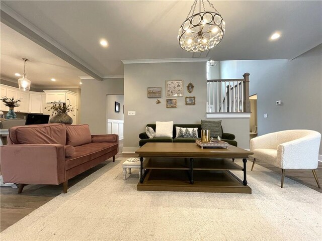 living room with light wood-type flooring, ornamental molding, and an inviting chandelier