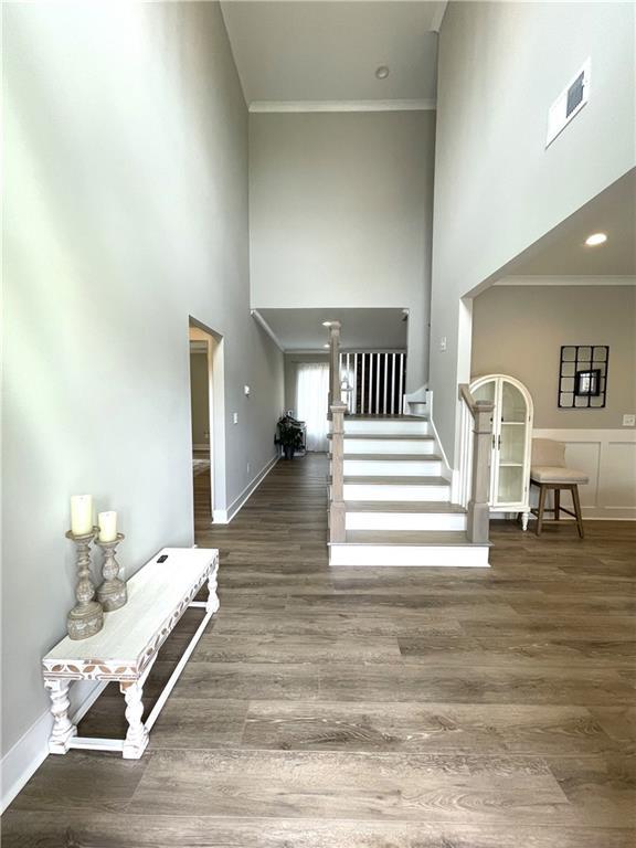 interior space featuring ornamental molding, a towering ceiling, and hardwood / wood-style floors