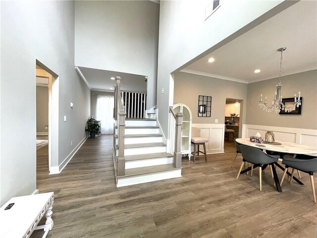 foyer entrance with ornamental molding, a high ceiling, a chandelier, and dark hardwood / wood-style floors