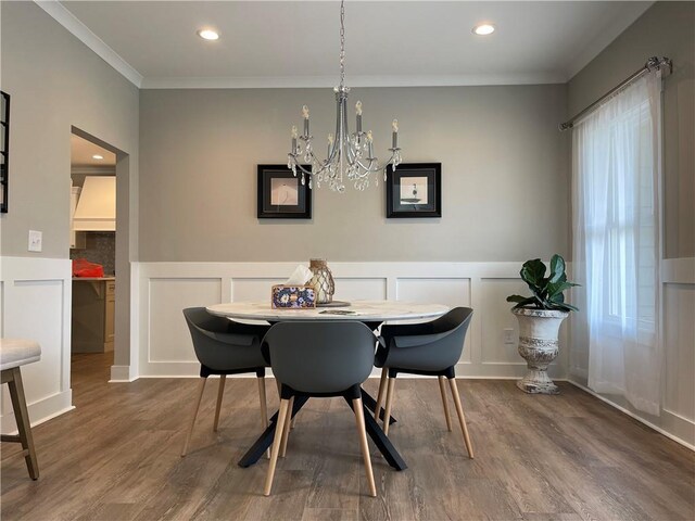 dining area with wood-type flooring, a chandelier, a healthy amount of sunlight, and crown molding