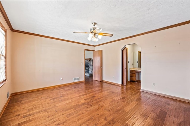 empty room featuring ceiling fan, crown molding, a textured ceiling, and light hardwood / wood-style flooring