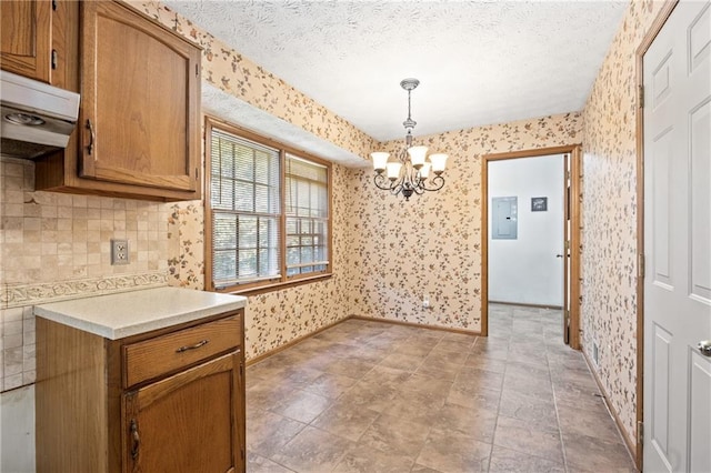 kitchen featuring a textured ceiling, a chandelier, hanging light fixtures, and electric panel