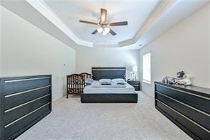 bedroom with carpet flooring, a raised ceiling, ceiling fan, and crown molding