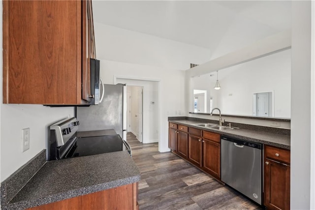 kitchen featuring lofted ceiling, appliances with stainless steel finishes, dark countertops, and a sink