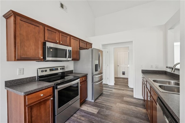 kitchen featuring a sink, visible vents, appliances with stainless steel finishes, dark countertops, and dark wood finished floors