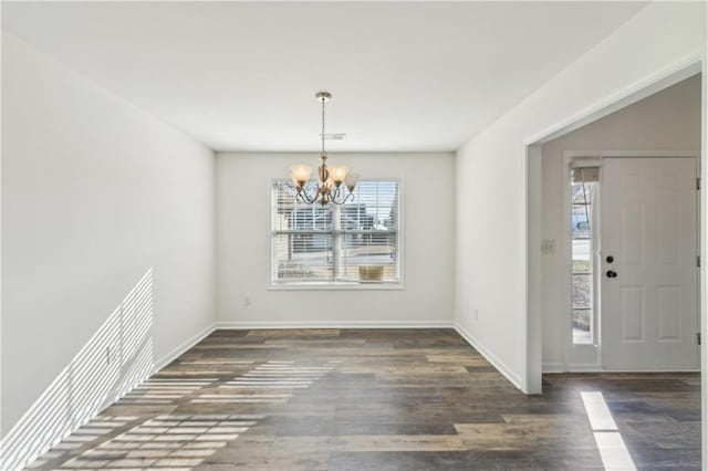 unfurnished dining area featuring wood finished floors, plenty of natural light, and an inviting chandelier